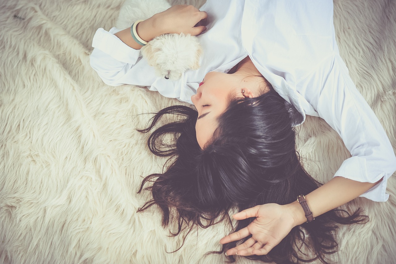 A woman lying on a fur rug with a dog