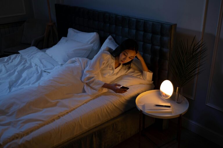 A woman lying in bed looking at her phone