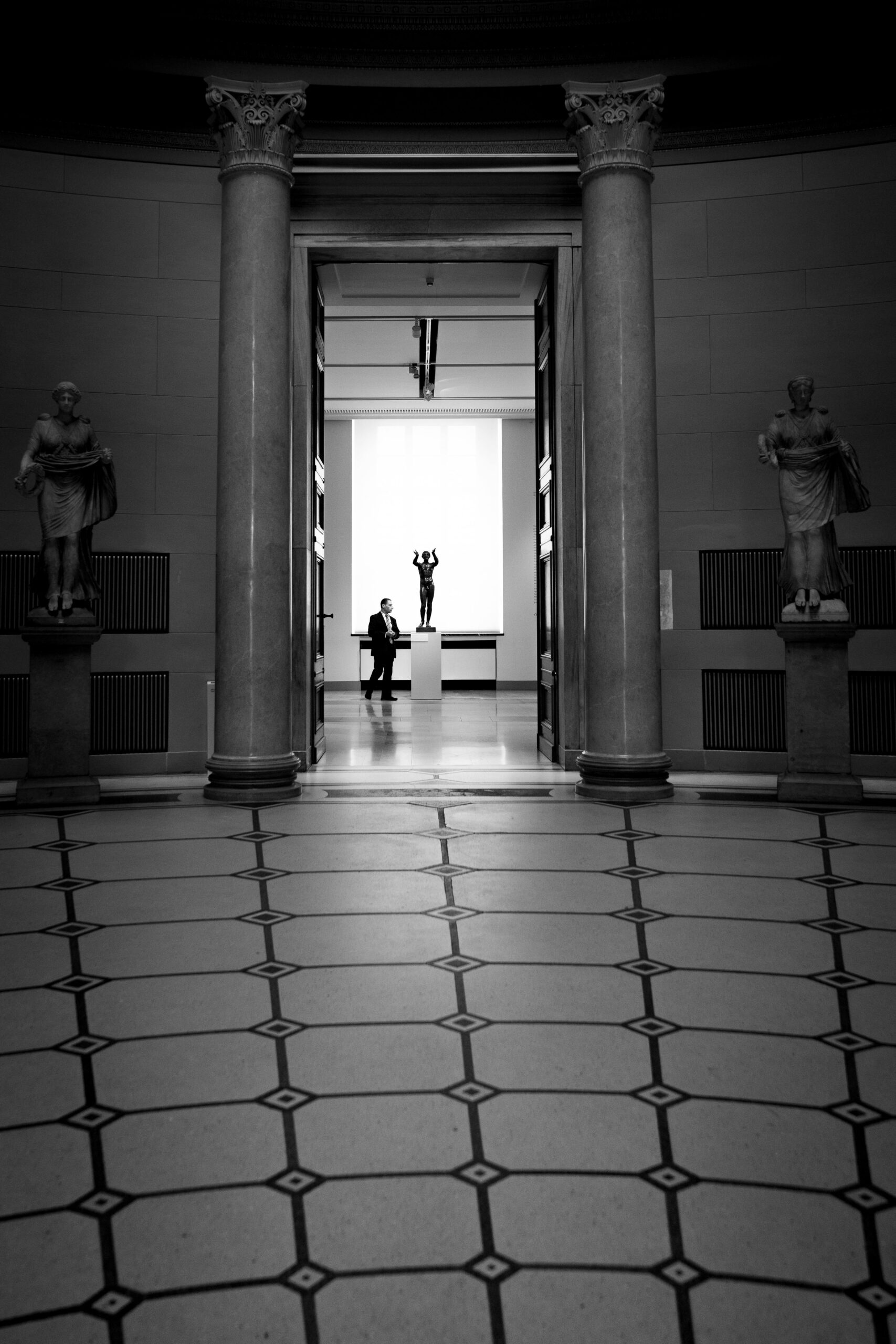 A man standing in a hallway with statues