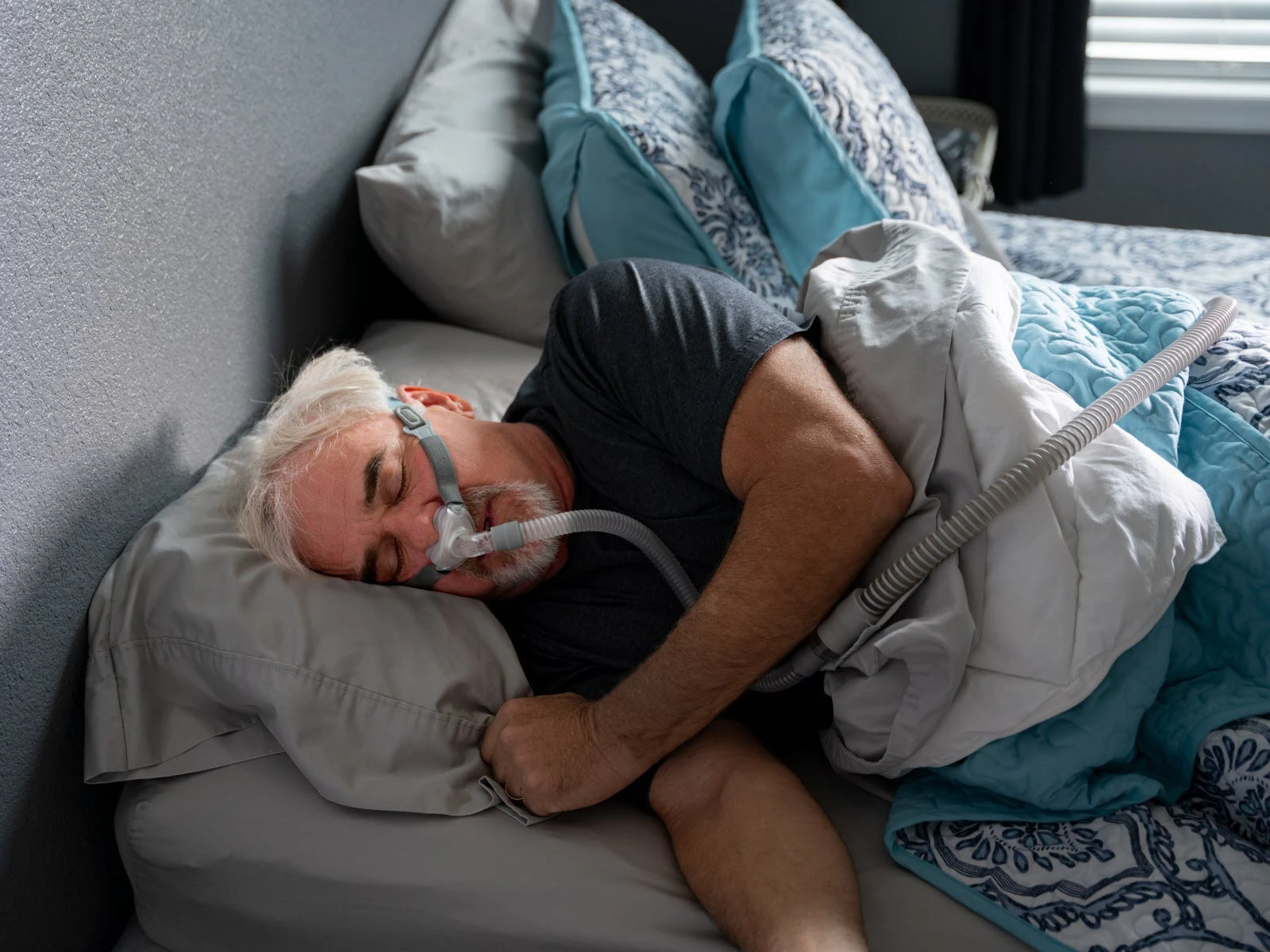 A man sleeping on his side with a nasal CPAP mask, showing side sleeping combined with PAP therapy